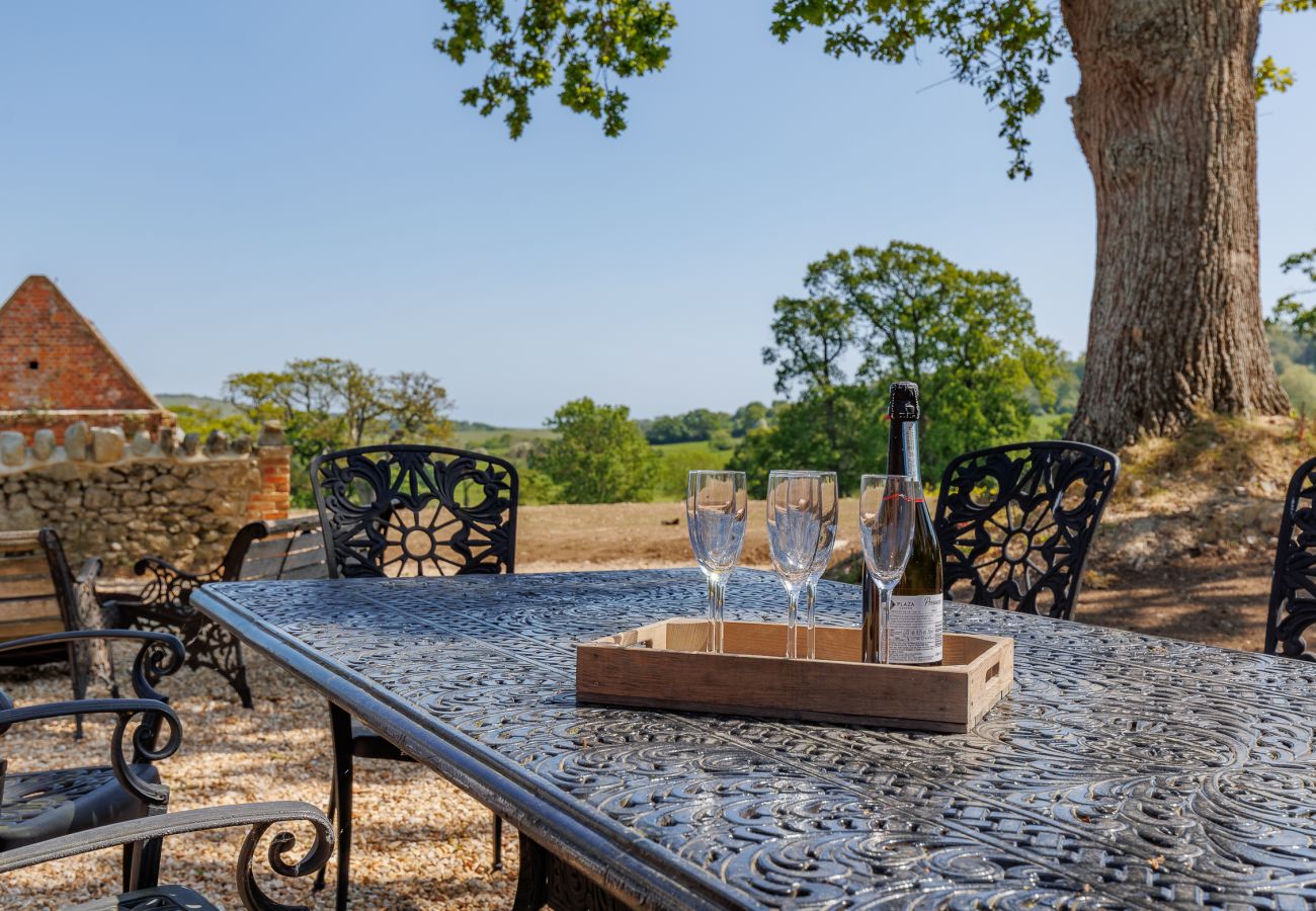 Outdoor dining area with firepit and BBQ at The Farmhouse at Nunwell holiday home on the Isle of Wight