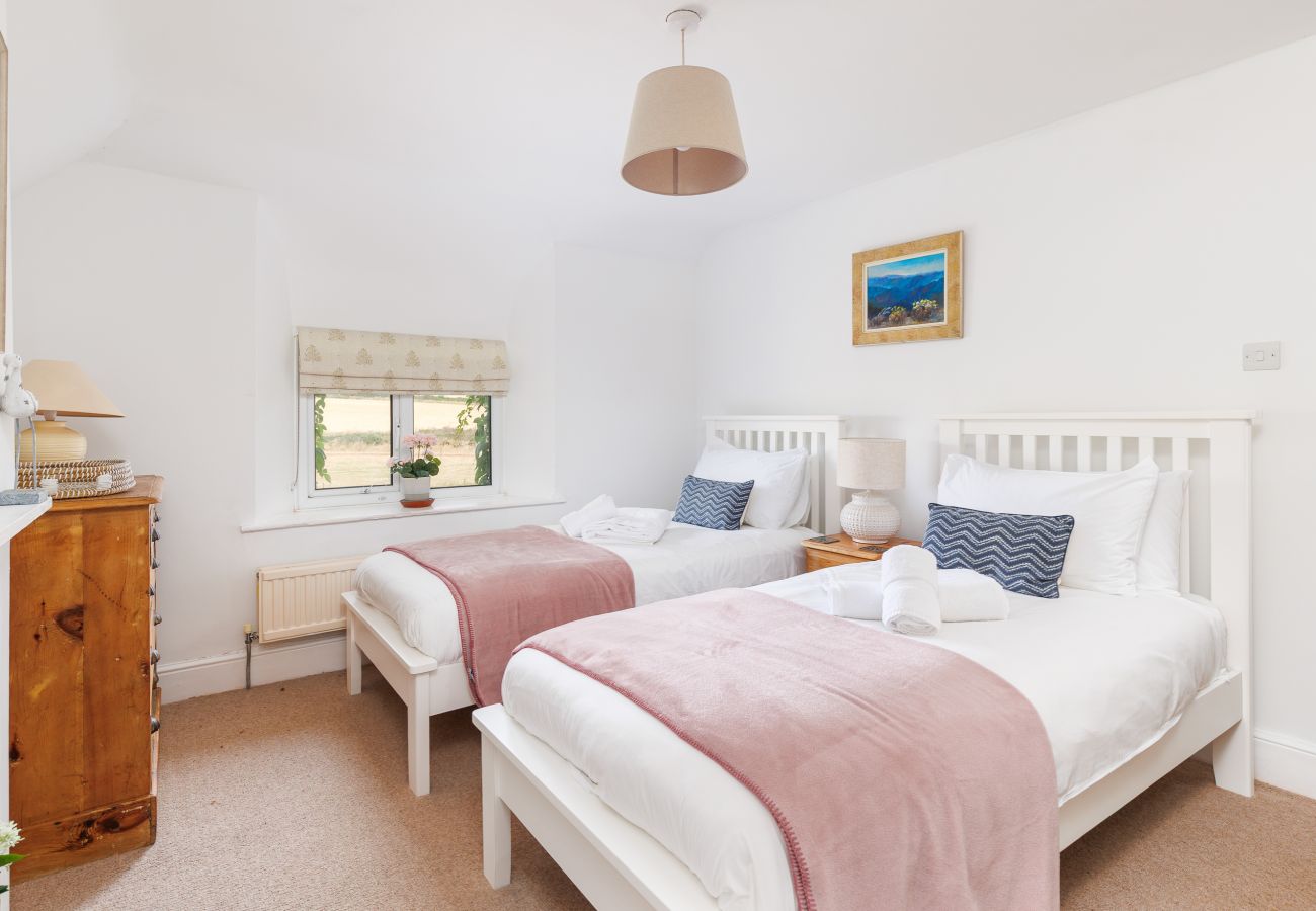 Twin bedroom with pink features and countryside views at Moon Chine Cottage on the Isle of Wight.